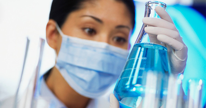 Female scientist looks at a flask containing bright blue liquid